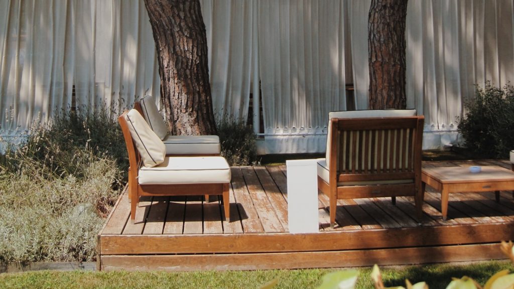 Terrasse extérieure en lames effet bois avec salon de jardin sous les pins