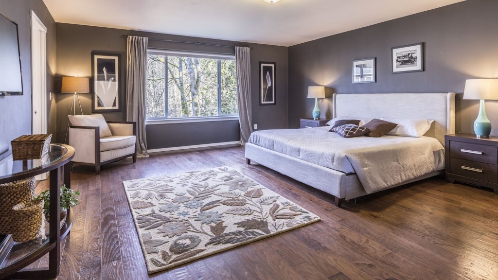 Chambre chaleureuse avec un sol en parquet bois et un grand lit